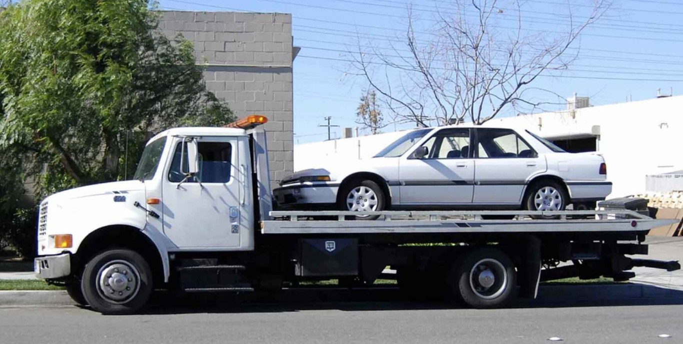 Flatbed tow truck safely transporting sedan in Hollister, CA